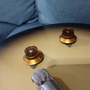 Detailní záběr na dvě jantarové plastové otočné knoflíky s číslicemi na těle kytary v žlutohnaté barvě. Na knoflících jsou viditelné čísla 0 a 10. Po…