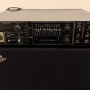 Černý rackový přístroj s nápisem Roland VOCODER SVC-350 položený na černém kombu značky Fender. Přední panel obsahuje různé přepínače, potenciometry…