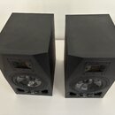Dva černé studiové monitory v plastovém provedení. Každý reproduktor obsahuje jeden výškový měnič s viditelnou žlutou membránou a jeden basový měnič.…