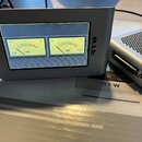 Stříbrný přístroj s displejem, na kterém jsou zobrazeny dva analogové VU metry. Na pravé straně šasi je svisle napsáno logo RTW. Vedle něj je vidět č…