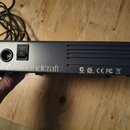 Černý elektronický přístroj s kovovým povrchem. Na přední straně je zapínací spínač s nápisem POWER a vstup pro napájení. Na spodní hraně je bílý náp…