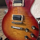 Elektrická kytara s trupem v červeno-žlutém sunburst provedení a viditelnou strukturou dřeva. Nástroj má dva humbuckery s krémovými rámečky, čtyři ov…