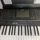Černý digitální klavír značky YAMAHA s modelem PSR-S. Nástroj má standardní klávesnici a ovládací panel s displejem, několika tlačítky a dvěma otočný…