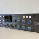 Šedý rackový studiový procesor s nápisem THE BUS+ 2-CHANNEL BUS COMPRESSOR & DYNAMIC EQUALISER. Přední panel obsahuje dva analogové VU metry, několik…