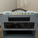 Zadní strana světle modrého kytarového komba s krémovými detaily a černou rukojetí. Na zadním panelu je nápis Blackstar Amplification Ltd a Made unde…
