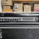 Černý basový zesilovač v kovovém šasi s nápisem Ampeg SVT-3 PRO. Přední panel obsahuje ovládací knofíky s popisky INPUT, GAIN, BASS, MIDRANGE, FREQUE…