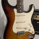 Elektrická kytara s tělem v provedení sunburst a bílým pickguardem. Kytara má tři snímače, tři ovládací knofíky s nápisy VOLUME a TONE a pětipozicovn…