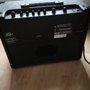 Černý kytarový kombo zesilovač s texturovaným povrchem. Na zadní straně je bílý nápis Peavey VYPYREX 1 a štítek s označením VYPYRE XT 220B. Horní pan…