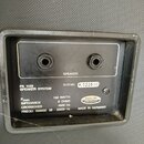 Fotografie zachycuje zadní panel reproduktoru s dvěma konektory pro připojení. Na panelu jsou nápisy SPEAKER, PA 1122 SPEAKER SYSTEM a technické spec…