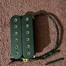 Černý humbucker s dvěma řadami šesti polových magnetů. Na spodní části levého snímače je svisle napsaný nápis DiMarzio. K nástroji vedou černé vodiče…