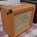 Kytarový kombozesilovač v oranžovém vinylu s béžovou textilní maskou. Na přední straně je bílý obdélníkový štítek s nápisem ORANGE a nad ním malý bar…