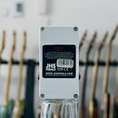 Zadní strana bílého efekt pedálu v kovovém provedení. Na spodní části je černá nálepka s nápisy JHS PEDALS, WWW.JHSPEDALS.COM a DESIGNED AND BUILT IN…