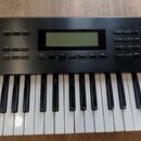 Černý elektronický klávesový nástroj s bílými a černými klávesami. Horní panel obsahuje displej, několik tlačítek s popisky jako VOLUME, PERFORMANCE,…