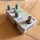 Kytarový efekt v bílém kovovém šasi s mramorovaným vzorem na horní straně. Na přístroji jsou tři šedé otočné knoflíky s popisky MIX, VOLUME a FEEDBAC…