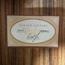 Fotografie detailu štítku vklepeného do těla akustické kytary. Na krémovém podkladu s hnědým rámem je uveden nápis TAYLOR GUITARS a ESTABLISHED IN 19…