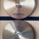 Dvě mosazné činely s viditelným broušením povrchu. Na obou je uveden nápis „istanbul Agop Handmade cymbals from Turkey“. Spodní činel má v dolní část…