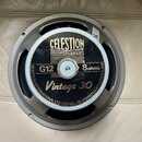 Kruhový reproduktor s šedým kovovým rámem. Na černém středovém štítku je zlatý nápis CELESTION LOUDSPEAKERS, označení G12, 8ohms a model Vintage 30.…
