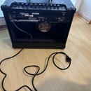 Zadní strana černého komba s ovládacím panelem na horní hraně. Na zadním panelu jsou vidět loga Roland a BOSS, nápisy AC IN, FOOT CONTROL (s označení…