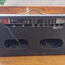 Zadní strana černého kytarového komba s koženým povrchem. Na horním panelu jsou nápisy LEO Fender MUSICAL INSTRUMENTS, MADE IN U.S.A., s přepínači ON…
