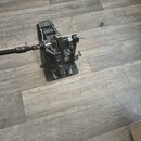 Černý bubnový pedál s kovovou konstrukcí a řetízkovým pohonem. Na povrchu jsou viditelné stopy používání a lehké znečištění. Žádné značky ani názvy m…