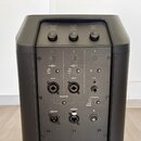 Černý reprodukěnice s ovládacími prvky na zadní straně. Horní část obsahuje tři otočné ovladače s nápisy VOLUME, TREBLE, BASS a REVERB. Střední panel…
