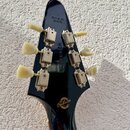 Zadní strana černé hlavy kytary s šesti ladicími kolíky z krémového plastu a kovovými mechanismy. Na horní části je nápis MADE IN USA. Uprostřed hlav…