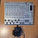 Bílý mixovací pult s nápisy BEHRINGER a EURORACK MX 2642A. Zařízení obsahuje více vstupních kanálů s modrými a červenými knoflíky a posuvníky v dolní…