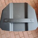 Černý, matný plastový nebo kovový objekt s hranatým tvarem a dvěma svislými žebry. Uprostřed je umístěna vodorovná lišta připevněná dvěma šrouby. Na…