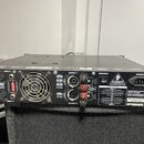 Zadní strana černého výkonového zesilovače značky BEHRINGER. Na přístroji jsou vidět vstupy INPUT 1 a INPUT 2, výstupy OUTPUT 1 a OUTPUT 2 s konektor…