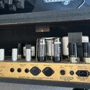 Interiér kytarového zesilovače s viditelnými elektronickými komponenty a vakuovými elektrony. Na zlatavém šasi je nápis Master Model 50w Mh2 Lead a t…