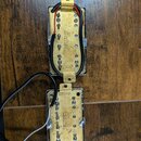 Dvě elektrické snímače s kovovými kryty v zlaté barvě. Na obou je vyryt nápis „Belcat“ a vedle něj v kroužku písmeno (horní snímač „B“, dolní snímač…