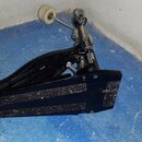 Černý basový pedál s kovovými mechanismy a stříbrným spojovacím hřídelí. Na bočním plastovém krytu je bílý nápis 8611. Povrch pedálu vykazuje známky…