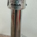 Detail kovového stojanu stříbrné barvy. Na horní části je nalepený štít s nápisy „ČESKOSLOVENSKÉ HUDEBNÍ NÁSTROJE STÁTNÍ PODNIK“, logem „Amati KRASLI…
