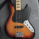 Elektrická basová kytara s korpusem v barevném přechodu od žluté přes červenou k černé. Nástroj má černý pickguard, čtyři struny a hmatník ze světléh…