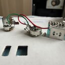 Fotografie zachycuje vnitřní zapojení elektroniky na bílém podkladu. Jsou zde vidět tři kovové komponenty propojené červeným a zeleným vodičem, z nic…