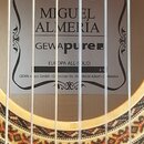 Detail vnitřku akustické kytary s viditelným štítkem. Na štítku jsou nápisy MIGUEL ALMERÍA, GEWApure, EUROPA ALL-SOLID a 4/4. Dole je uveden text GEW…