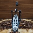 Fotografie zobrazuje černý bicí pedál s kovovými prvky. Na šlapce je viditelný nápis V4 v kruhu a ve spodní části značka BASIX. Povrch šlapky je stří…