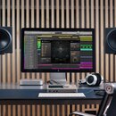 Fotografie zachycuje domácí studio s černými studiovými monitory na stojaních, počítačem iMac a bílými sluchatky. Na stole je umístěna stříbrná zvuko…