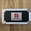Stříbrný transportní kufr s kovovými rohy a hranami. Uprostřed je černý povrch s bílým čtvercovým štítkem, na kterém je červené logo SE a nápis sE EL…