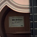 Detail vnitřku akustické basy s viditelným štítkem. Na štítku je nápis WARWICK ELECTRO-ACOUSTIC BASS, Alien Rockbass a dále WAC1575 10PP SAG F2. U po…