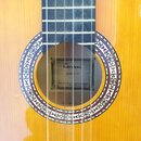 Detail akustické kytary s žlutým povrchem a ozdobnou rozetou kolem otvoru. Uvnitř otvoru je štítek s nápisy Tenson, CLASSIC 4/4 a ANOTHER QUALITY PRO…