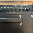 Detailní pohled na ovládací panel a úchytku černého kytarového komba. Na ovládacím panelu jsou nápisy PLIFIER, EQUALIZER (GAIN, VOLUME, BASS, MIDDLE,…