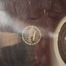 Detail kovového činely s koncentrickými rýhami na povrchu. Uprostřed je vyražené logo PAISTE a sériové číslo 16008682. Kolem loga je nápis HAND MADE…
