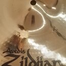 Zlatavý kovový činel s centrálním otvorem. Na povrchu je černý nápis Zildjian a nad ním menší jméno Avedis. V horní části je čitelný nápis CRASH a po…