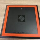 Zadní strana černého kontroléru s oranžovým rámem. Uprostřed je nápis LAUNCHPAD PRO a nad ním čítelné sériové číslo AZWKC04160031 a kód MK2. V dolní…