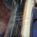 Detail kovového, stříbrného nástroje s engravingsm. Je na něm vyryt nápis „V KOHLERT & SYN KRASLICE C. & R.“ a pod ním další, méně čitelný řádek text…