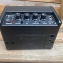 Černý kompaktní kytarový zesilovač s ovládacími knoflíky Gain, Volume, EQ a Delay. Na horní části je vidět logo FLY a nápis 3 WATT MINI AMP, v zadní…