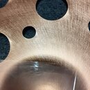 Detailní záběr na bronzový činel s otvory v ploše. Na povrchu je černý nápis pAiste a pod ním modelové označení pst X s doplňkem 16" SWISS THIN CRASH…