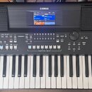 Černý digitální klavír značky YAMAHA s modelem PSR-SX600. Nástroj má v horní části displej a dvě integrovaná reproduktory s mřížkou. Ovládací panel o…