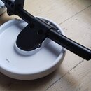 Černý kovový stojan s úchytem, který je upevněn na kulatém bílém plastovém podstavci. Na spodní straně bílého podstavce je vyražen nápis 19E5450. Pov…